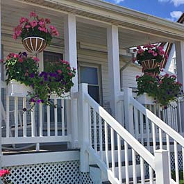 rail planters and hanging baskets on white porch