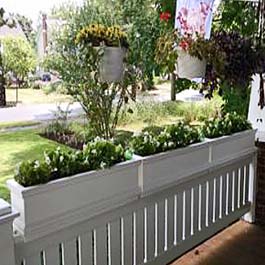white flower boxes sit on top of porch railings