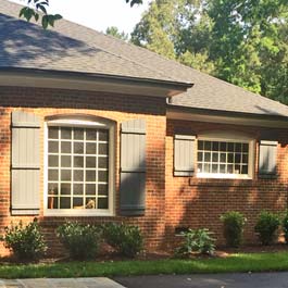 board and batten shutters with arch top on brick home