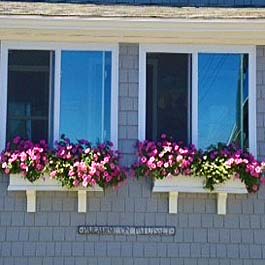 two adjacent white window boxes installed on shake siding